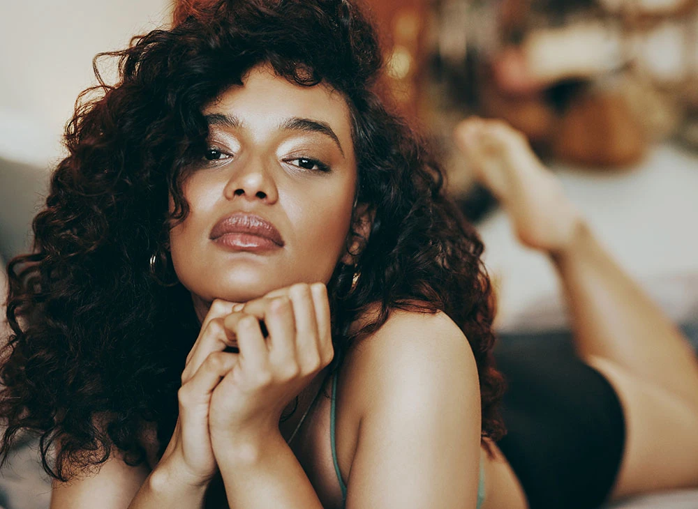 curly haired woman laying on stomach with with glowing skin | Ottawa Plastic Surgery in Ottawa, Canada