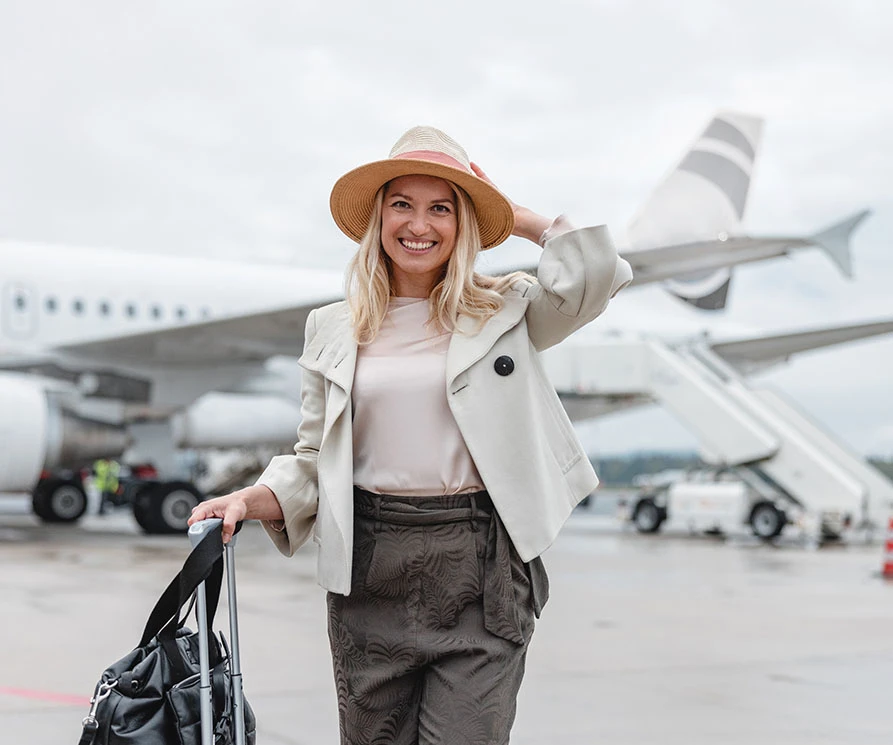 Woman with luggage walking away from plane | Ottawa Plastic Surgery in Ottawa, Canada